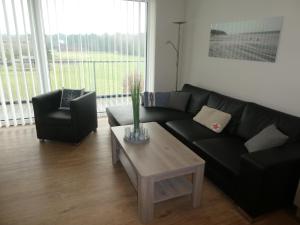 a living room with a black couch and a coffee table at Quartier Hohe Geest 17 - Nord Seestern - a69854 in Cuxhaven