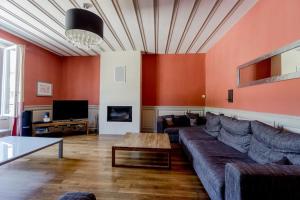 ein Wohnzimmer mit einem Sofa und einem TV in der Unterkunft Gite de charme Le Clos Michel 14 personnes piscine in Briord