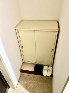 une petite étagère dans une pièce avec deux chaussures dans l'établissement Shinjuku gochome Hana house, à Tokyo