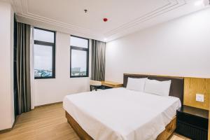 1 dormitorio con 1 cama blanca grande y ventanas en Hệ Thống Sen Biển Hotel FLC Sầm Sơn - Restaurant Luxury en Sầm Sơn