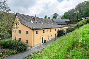 un grand bâtiment jaune avec un toit noir dans l'établissement Ferienwohnungen 'am Waldrand', à Hartmannsbach