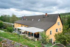 une grande maison jaune avec un toit noir dans l'établissement Ferienwohnungen 'am Waldrand', à Hartmannsbach