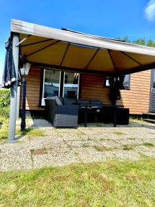 a patio with an umbrella and chairs under a house at Chalet op 5 ster CampingPark Capfun de Bongerd in Tuitjenhorn