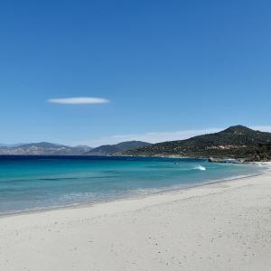 une plage avec de l'eau bleue et des montagnes en arrière-plan dans l'établissement La perle de lozari, Duplex vue mer, Belgodère, L'île rousse, Corse, à Belgodère