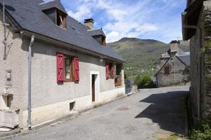 a building with red shuttered windows with mountains in the background at La Nabias - Maison de montagne in Adervielle