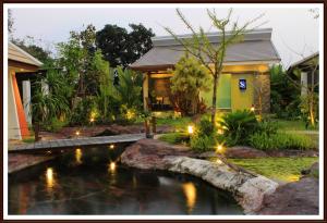 einen Garten mit einem Teich vor einem Haus in der Unterkunft Saabpaiboon Grand Resort in Ban Talat