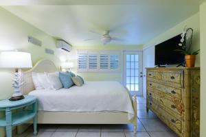 a bedroom with a bed with a television and a dresser at Kona Kai Resort and Gallery in Key Largo