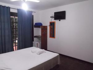 a bedroom with a bed and a tv on the wall at Pousada Casa dos Sonhos in Rio das Ostras