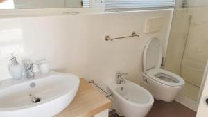 a white bathroom with a sink and a toilet at One bedroom bungalow with shared pool and wifi at Lizzano 6 km away from the beach in Lizzano