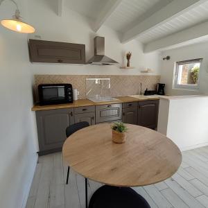 eine Küche mit einem Holztisch mit Stühlen und einem Waschbecken in der Unterkunft Maison 2 personnes ILE D'YEU - 2 personnes + 2 vélos in Ker Pierre Borny