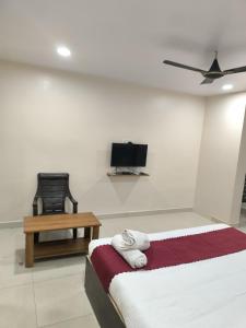 a bedroom with a bed and a chair and a tv at archana GRAND in Visakhapatnam