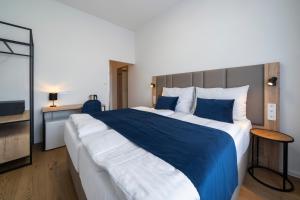 Hotel LEON في براغ: غرفة نوم بسرير كبير وملاءات زرقاء وبيضاء