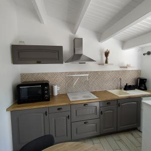 eine Küche mit einer Spüle und einer Mikrowelle in der Unterkunft Maison 2 personnes ILE D'YEU - 2 personnes + 2 vélos in Ker Pierre Borny