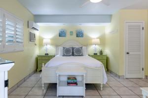 a bedroom with a white bed and yellow walls at Kona Kai Resort and Gallery in Key Largo