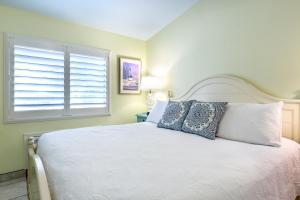 a bedroom with a white bed and a window at Kona Kai Resort and Gallery in Key Largo