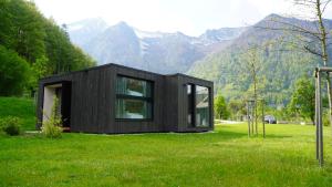 una casa negra en un campo con montañas en el fondo en The Campus Alps - tiny homes, en Hieflau
