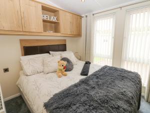 a teddy bear sitting on a bed in a bedroom at Plot 32 in Carlisle