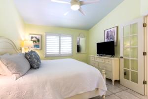 a bedroom with a white bed and a flat screen tv at Kona Kai Resort and Gallery in Key Largo