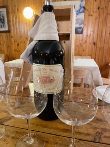 una bottiglia di vino seduta su un tavolo con due bicchieri da vino di Albergo K2 a Madesimo