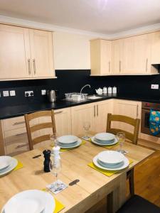 - une cuisine avec une table en bois, des assiettes et des verres à vin dans l'établissement Sanctuary Cottage - close to the centre of Anstruther, à Fife
