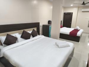 - une chambre avec 2 lits et des draps blancs dans l'établissement archana GRAND, à Visakhapatnam