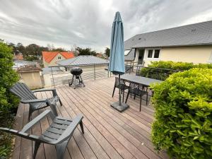 a wooden deck with a grill and an umbrella at Les Apparts de St Mart in Bréhal