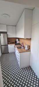 a kitchen with white cabinets and a black and white tiled floor at Apartmán Petzvalova 51 in Myslava