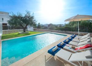 einen Pool mit Liegestühlen und einem Sonnenschirm in der Unterkunft Marinella Blanca in Cacla D'or