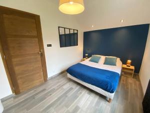 a bedroom with a bed with a blue blanket and a door at Le joli bois 12 personnes 5/ch spa/sauna Gérardmer in Gérardmer