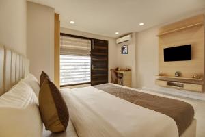 um quarto com uma cama grande e uma televisão em Limewood Stay - Corporate Huda City Centre em Gurgaon