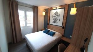 ein kleines Schlafzimmer mit einem Bett mit blauen Kissen in der Unterkunft Logis Hôtel - Les Pasteliers in Lavaur