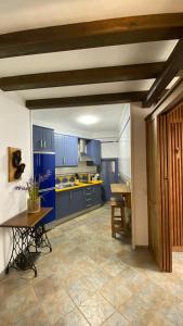 eine große Küche mit blauen Schränken und einem Tisch in der Unterkunft “La Carpintería” in Prado del Rey