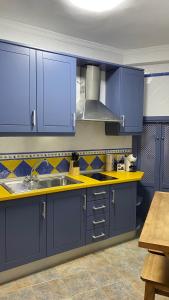 una cocina con armarios azules y fregadero en “La Carpintería” en Prado del Rey