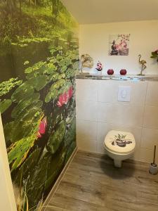 a bathroom with a painting on the wall and a toilet at Ferienwohnung Emma in Steinwiesen