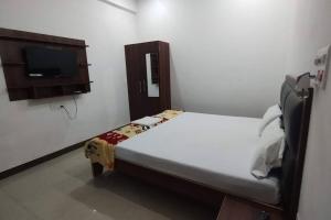 a small room with a bed and a tv at Champaran Home Deluxe in Varanasi