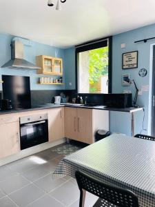 cocina con paredes azules, mesa y ventana en Cocon Familial Proche Disneyland Paris en Quincy-Voisins