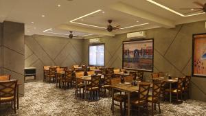 a restaurant with tables and chairs in a room at Hotel The Excellency in Surat