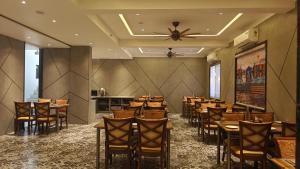 a dining room with a bunch of tables and chairs at Hotel The Excellency in Surat