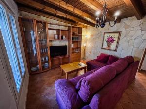 sala de estar con sofá púrpura y pared de piedra en Villa Rosal- Solo familias y parejas, en Conil de la Frontera