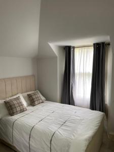 uma cama com duas almofadas num quarto com uma janela em Merchiston Residence em Edimburgo