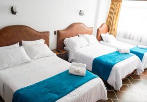 a hotel room with two beds and a window at HOTEL ENCANTO COLONIAL in Villa de Leyva