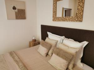 1 dormitorio con cama con almohadas y espejo en Entre Mer et Vignes, en Nissan-lez-Enserune