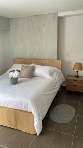 - une chambre dotée d'un grand lit avec des draps et des oreillers blancs dans l'établissement Apartamento en Zima con aire acondicionado, à Pereira