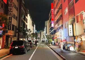 uma rua da cidade à noite com carros estacionados na rua em Hills Hotel Gotanda em Tóquio