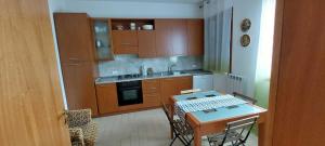 a kitchen with wooden cabinets and a table with chairs at B&B Marku in Dëllinjë