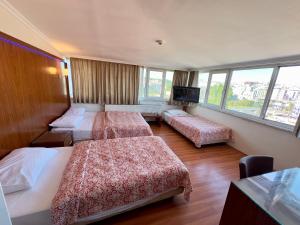 イスタンブールにあるHotel Naylaのベッド3台、薄型テレビが備わるホテルルームです。