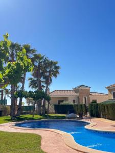 una piscina frente a una casa con palmeras en Impresionante villa PISCINA JARDÍN ALTAONA GOLF en Murcia