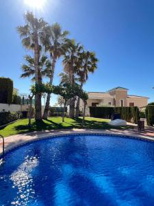 una gran piscina con palmeras frente a una casa en Impresionante villa PISCINA JARDÍN ALTAONA GOLF, en Murcia