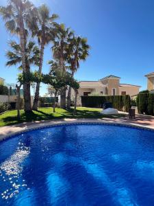 una gran piscina azul con palmeras en Impresionante villa PISCINA JARDÍN ALTAONA GOLF, en Murcia