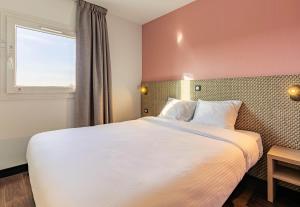 a bedroom with a large bed and a window at B&B HOTEL Colmar Lumière in Colmar